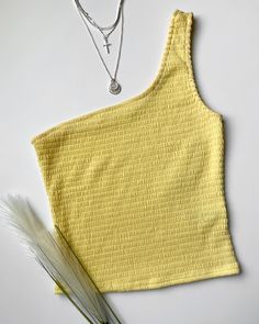 This style is the perfect addition to your spring wardrobe. It features a gorgeous spring yellow, one-shoulder neckline, and is smocked all around. Wear it casually or dress it up to your next event. More details: - Fits true to size for most - Stretchy - Cropped (Sits right below the navel on the model) - Color may vary due to the lighting - Model is wearing a size small Model Details Height 5'7 | Chest 34" Waist 27" Hips 36.5" | Weight 118lbs | Wears a US size small in tops and dresses. See ou Summer Cropped Yellow Top, Yellow Cropped Cotton Top, Trendy Yellow Crop Top, Fitted Yellow Crop Top, Yellow Cropped Cotton Crop Top, Yellow Tank Top, Fashion Forecasting, Yellow Top, Color Block Top