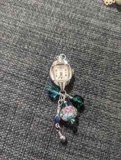 This is a Vintage DeWitt wrist watch turned into a watch pendant necklace with charms. The watch does not currently run, not sure what year it is either, but it is 17 jewels. This is a beautiful upcycled watch pendant necklace. The charms are green and blue. One of the beads has a pink rose in it. Disclaimer ( keep out of reach of children, small objects can cause choking.) Necklace With Charms, Watch Pendant, Watch Jewelry, Recycled Jewelry, Small Objects, Upcycled Vintage, Watch Necklace, Watches Jewelry, Vintage Watches