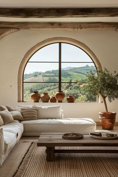 a living room filled with furniture and a large window overlooking the countryside below it's arched windows