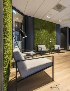 a living room filled with lots of furniture next to a wall covered in green plants