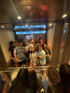 a group of young people standing in front of a glass elevator with their arms around each other