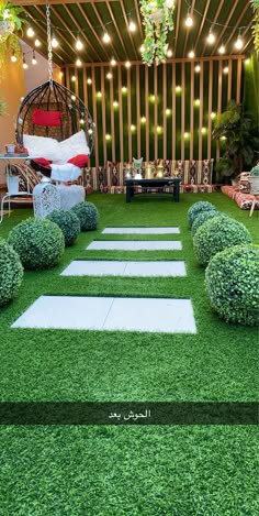 an outdoor area with grass and stepping stones in the center, surrounded by hanging lights