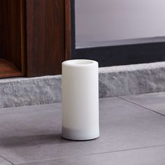 a white vase sitting on the ground in front of a door