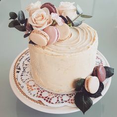 a cake with frosting and flowers sitting on a doily next to a glass table