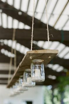 some glass jars hanging from a wooden beam