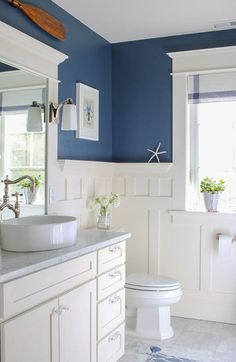 a bathroom with blue walls and white cabinets