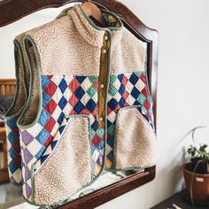 a jacket is hanging on a mirror near a potted plant