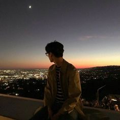 a young man sitting on top of a roof at night