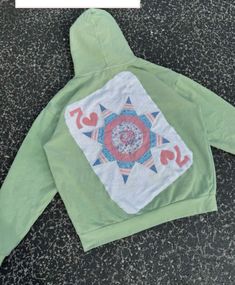 the back of a green hoodie with an embroidered design on it