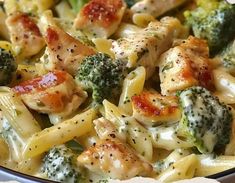 a bowl filled with chicken, broccoli and pasta covered in seasoning on top of a table