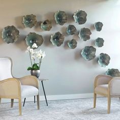 two chairs are facing each other in front of a wall with silver flowers on it