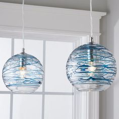 two blue and white glass globe lights hanging from a ceiling in front of a window