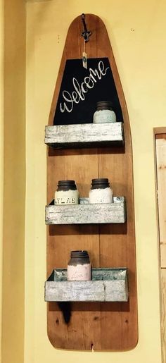 a wooden sign that says welcome hanging on a wall next to shelves with jars and containers