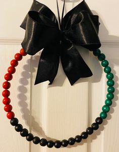 a black and red beaded necklace hangs on a door with a bow at the top