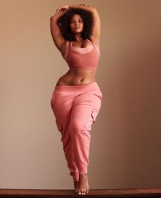 a woman standing on top of a wooden table wearing pink pants and a tank top