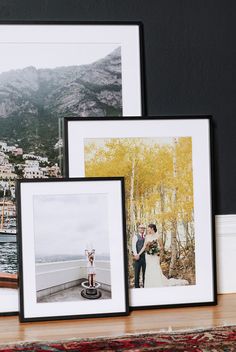 three framed photographs sitting next to each other on a wooden floor near a wall with mountains in the background