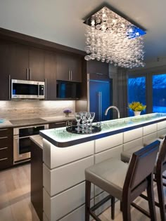 a modern kitchen with an island counter and bar stools in front of the window