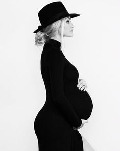 a pregnant woman in a black dress and hat