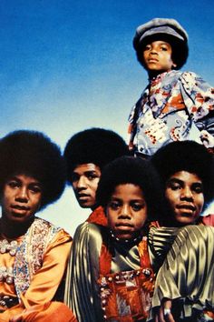 the jacksons pose for a portrait in front of a blue sky, wearing colorful clothing