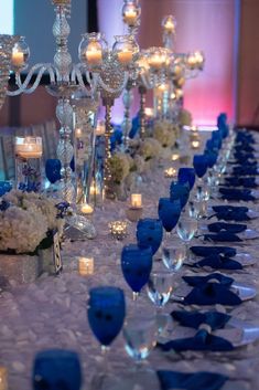 the table is set with candles and blue glassware for an elegant dinner or reception