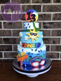 a three tiered birthday cake decorated with cartoon characters and decorations on a table in front of a brick wall