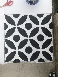 a pair of black and white shoes sitting next to a wall with a stencil design on it