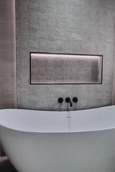 a white bath tub sitting inside of a bathroom next to a wall mounted toilet paper dispenser