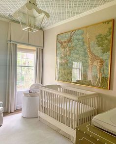 a baby's room with a giraffe painting on the wall next to a crib