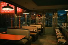 the interior of a restaurant with many tables and chairs in front of large windows at night