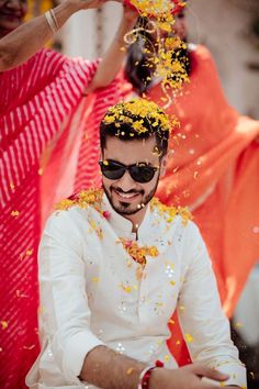 a man in white shirt and sunglasses throwing yellow confetti on his face while sitting down