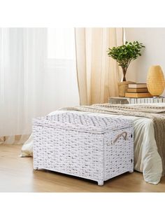 a white wicker storage box sitting on top of a wooden floor next to a bed