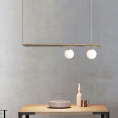 a wooden table with two lights hanging from it's sides and a white bowl on top