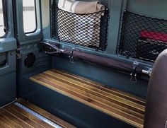 the interior of a vehicle with wood flooring and metal mesh partitions on it