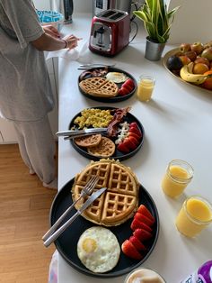 a woman standing in front of a table filled with waffles and other breakfast foods