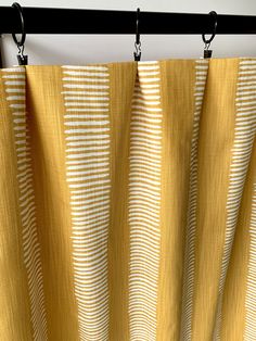 yellow and white curtains hanging on a black rod