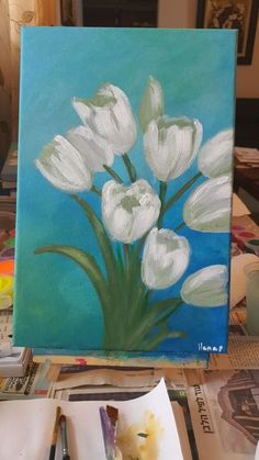 a painting of white tulips on a blue background with paintbrushes next to it