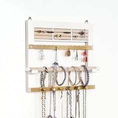 a white wall mounted jewelry rack with lots of necklaces