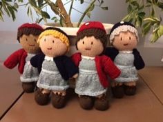 a group of knitted dolls sitting on top of a table next to a potted plant