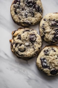 four chocolate chip cookies sitting on top of a marble counter