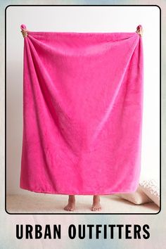 a person standing under a pink towel with the words urban outfitters on it