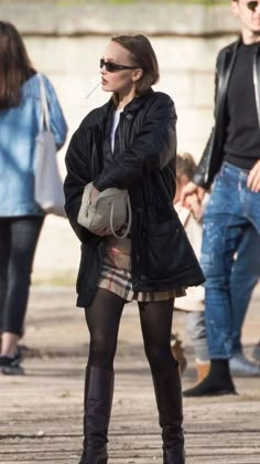 a woman in black jacket and plaid skirt standing next to a man