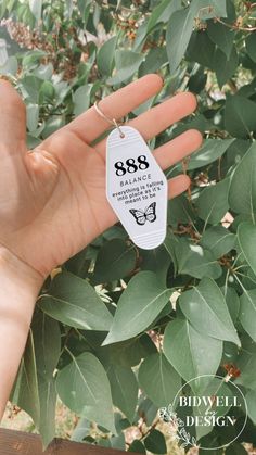 a hand holding a white tag with the number 999 on it and an image of a butterfly