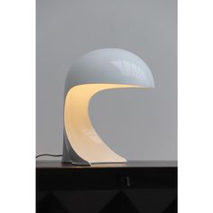 a lamp that is sitting on top of a wooden table in front of a gray wall