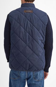 One of the brand's bestselling styles for 30 years, this boldly quilted vest offers oversized patch pockets, a ring-pull zip and an insulated stand collar to keep you cozy in transitional weather. Front zip closure Stand collar Front patch pockets Lined, with 100% polyester fill 90% polyester, 10% polyamide with 100% cotton contrast Machine wash, line dry Made in Vietnam Navy Sleeveless Outerwear With Pockets, Fall Cotton Quilted Vest, Fall Quilted Cotton Vest, Winter Quilted Cotton Vest, Quilted Nylon Vest For Cold Weather, Outdoor Nylon Vest With Padded Collar, Barbour Vest, Quilted Black Nylon Vest, Barbour Liddesdale