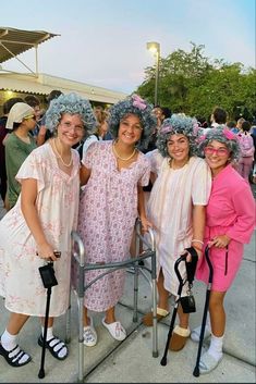 three women with blue wigs and crutches pose for a photo in front of a crowd