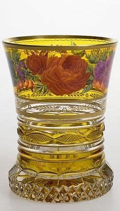 a yellow glass vase with flowers painted on the side and gold trimming around it