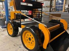 a yellow and black snow plow sitting on top of a floor