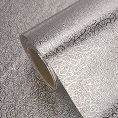 a roll of metallic foil on top of a white table cloth with black and silver designs