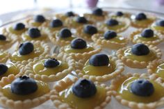 small pastries with olives and blueberries are arranged on a glass platter