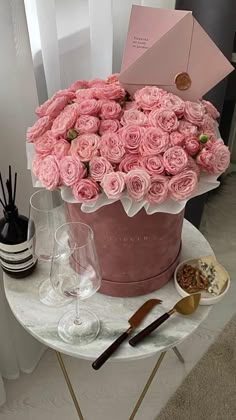 a large pink flower pot sitting on top of a table next to some wine glasses